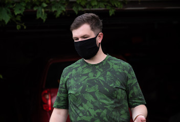 Obraz premium Social distance. Stop virus ! Young Man in Textile black cotton mask 