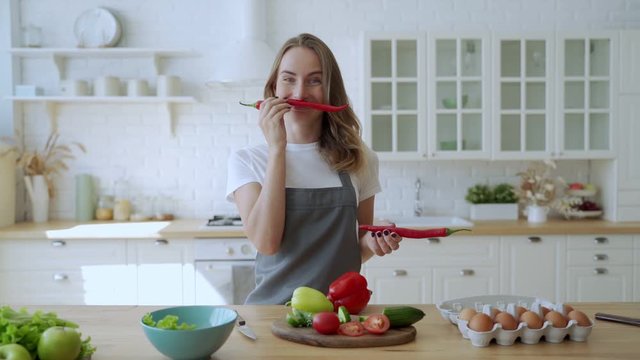 Young woman having fun with pepper in the kitchen