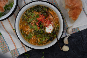 Spinach green peas and brown rice soup topped with sour cream, served in enameled bowl with home baked bread