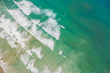 Cape Town, Western Cape / South Africa - 06/30/2020: Aerial photo of surfer and waves at Muizenberg Beach