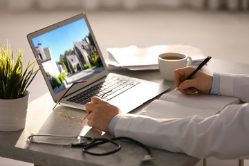 Fototapeta na wymiar Real estate agency online service. Doctor choosing new house via laptop, closeup