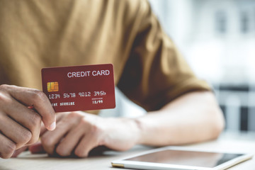 Businessman hand hold credit card to online shopping on computer tablet from home, payment e-commerce, internet banking, spending money