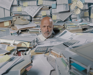 Disappointed stressed businessman overwhelmed by paperwork