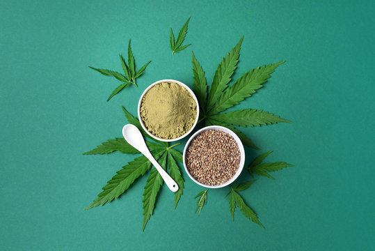 Different types of hemp extract products - cannabis leaves, seeds, protein powder, flour on green background. Top view. Copy space. Flat lay
