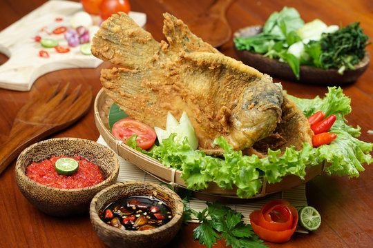 Flying fried fish with raw sambal on a wooden table. Usually used for menu list pictures or food pictures in restaurants. Top view