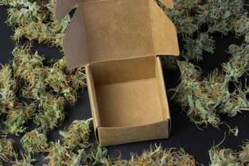 Empty open brown box on cannabis background top view