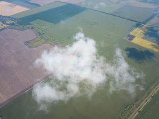 High flight in the clouds over agricultural fields.