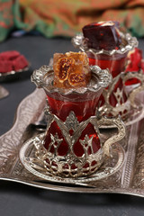 Fototapeta na wymiar Pomegranate tea and turkish delight on metal tray on dark background, Closeup
