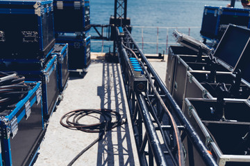 Installation of professional sound, light, video and stage equipment for a concert. Stage lighting equipment is clamped on a truss for lifting. Flight cases with cables..