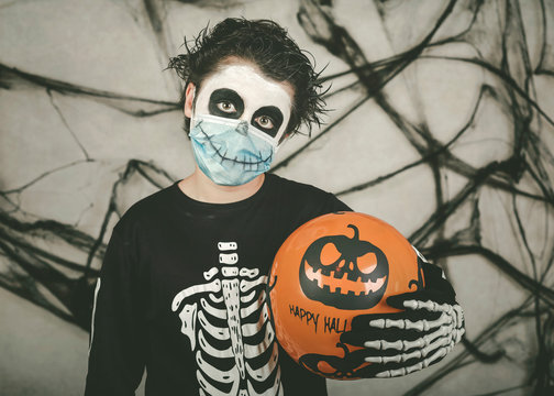 Happy Halloween. kid wearing medical mask in a skeleton costume with halloween balloon