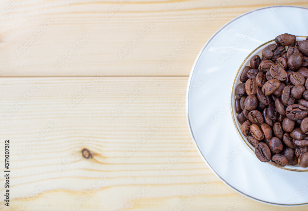 Poster white mug with cup of coffee beans on wooden background with selective focus and crop fragment