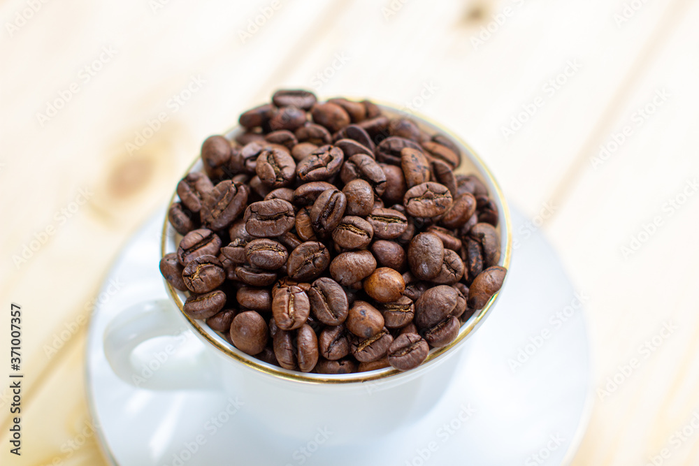 Poster white mug with cup of coffee beans on wooden background with selective focus and crop fragment