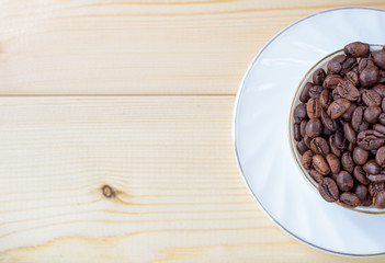 White mug with Cup of coffee beans on wooden background with selective focus and crop fragment