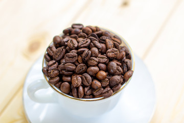 White mug with Cup of coffee beans on wooden background with selective focus and crop fragment