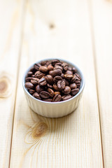 White mug with Cup of coffee beans on wooden background with selective focus and crop fragment