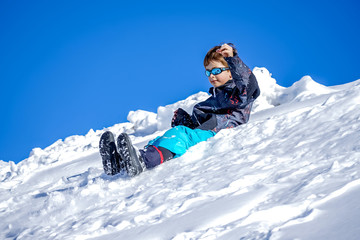 Fototapeta na wymiar Young Boy Glides Down On The Snow Mountain.