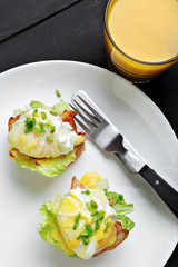 Top view of toasted buns with bacon, lettuce and poached egg
