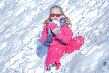 Fototapeta na wymiar Young Girl Sitting On The Snow Mountain and playing with snow ball .