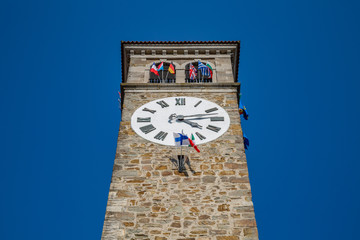 View of clock tower with flags of many different countries against blue sky background.