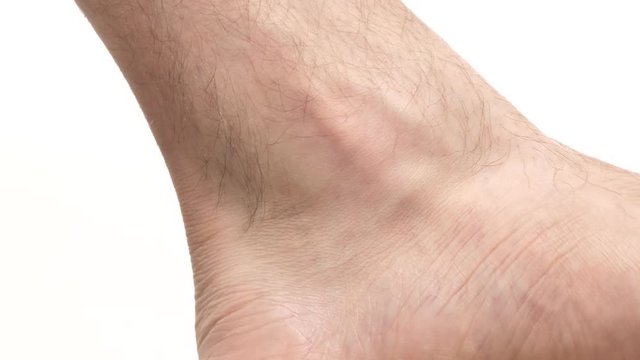 Closeup on the ankle of a young man. Human body part over a white screen background.