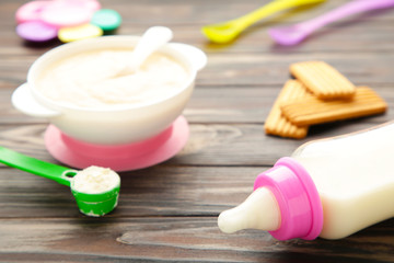 Bowl with baby food with toys on brown background