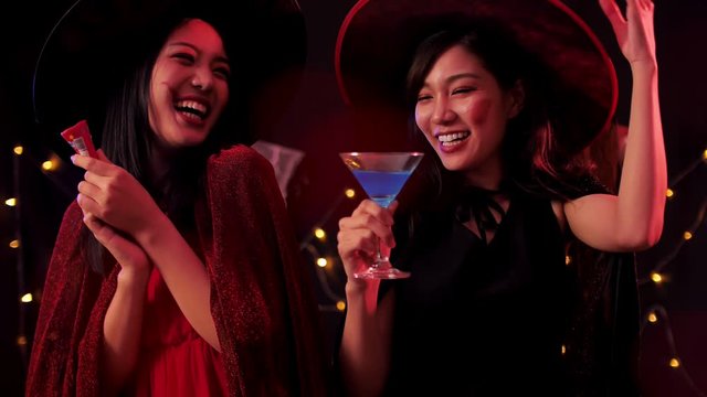 Two young women in witch costumes having fun at Halloween party.