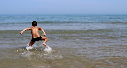 Fototapeta na wymiar Bambino che corre nel mare - divertimento