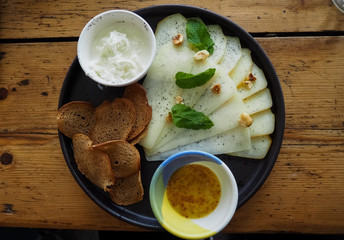 photo of a clay plate with different cheeses and bread