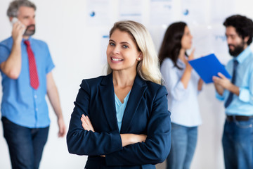 Blond german businesswoman with international team in background