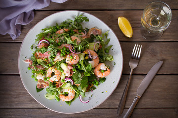 Shrimp salad with bacon, cucumber and radish on wooden background close up. Clean eating