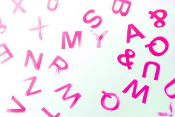 Silhouettes of alphabet letters on pink background. English letters stamp. Top view. Copy space for your creative design