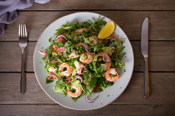 Shrimp salad with bacon, cucumber and radish on wooden background close up. Clean eating. Flat lay, overhead