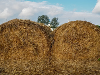 photo of two haystacks over a cloudy sky