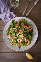 Shrimp salad with bacon, cucumber and radish on wooden background close up. Clean eating. Flat lay, overhead