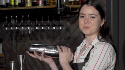 Cheerful female bartender preparing a drink for a customer. Lovely young woman enjoying working at her bar, making cocktails for clients. Occupation, job concept