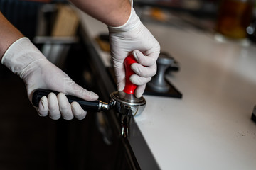 Barista makes coffee and holds a porta filter in her hands and presses coffee.