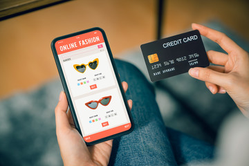 Hand holding smartphone and using application shopping online with payment by credit card online.