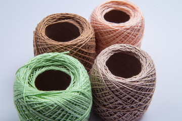 Quatro novelos de linha com cores variadas sobre superfície branca.