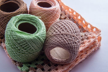 Quatro novelos de linha em cima de uma peça de crochê.