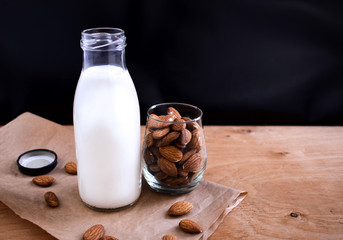 Homemade almond milk in glass bootle almond on the wooden table. Organic alternative milk. Copy space. Vegan milk from almonds nuts.