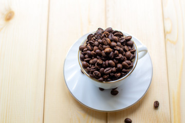 White mug with Cup of coffee beans on wooden background with selective focus and crop fragment