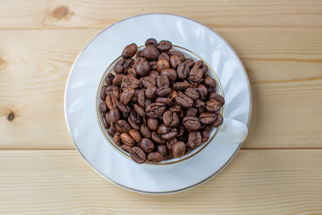 White mug with Cup of coffee beans on wooden background with selective focus and crop fragment