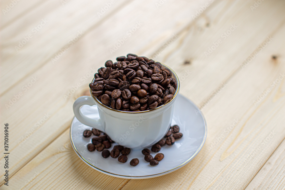Poster white mug with cup of coffee beans on wooden background with selective focus and crop fragment