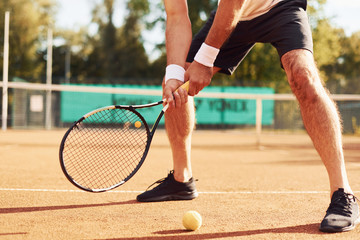 Close up view of senior man in white shirt and black sportive shorts that is on tennis court