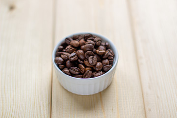 White mug with Cup of coffee beans on wooden background with selective focus and crop fragment