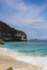 Fototapeta na wymiar Suwehan beach on Nusa Penida Island, Bali, Indonesia. Amazing view, white sand beach with rocky mountains and azure lagoon with clear water of Indian Ocean 