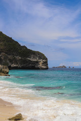 Fototapeta na wymiar Suwehan beach on Nusa Penida Island, Bali, Indonesia. Amazing view, white sand beach with rocky mountains and azure lagoon with clear water of Indian Ocean 