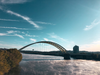 Fototapeta na wymiar Mist rises from the Ohio River early in the morning as it floats under the yellow bridge.