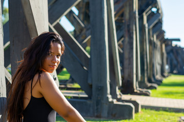 young woman sitting or standing next to a wooden and iron bridge