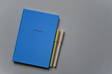 Blue notebook with two pens on a blue paper background. Top view. Close-up. Flat lay.